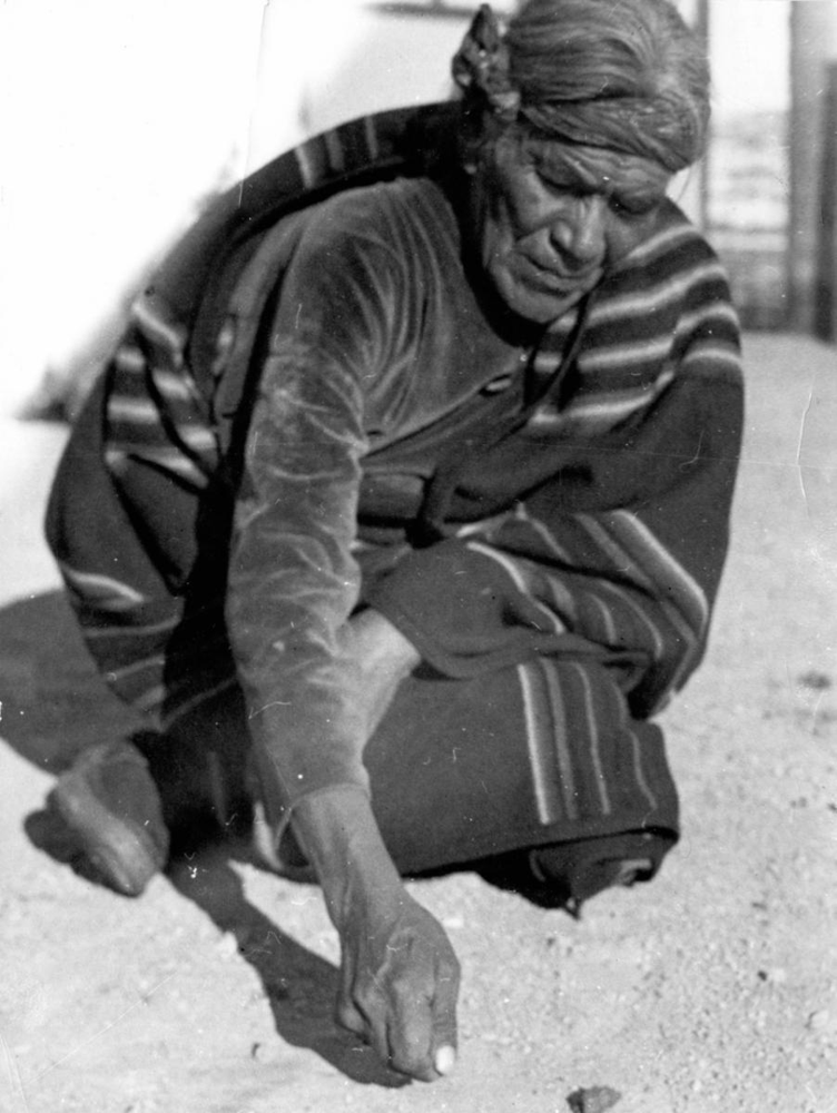 Hosteen Klah demonstrating a sandpainting, New Mexico, early 1930s. In this candid photograph by Franc J. Newcomb, Klah (center) is creating a ceremonial sandpainting on the ground as part of a healing ritual. Newcomb was a trader’s wife and close friend who documented many scenes of Klah’s life.